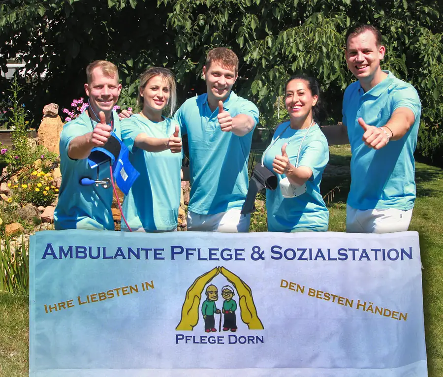 Das Team von Pflege Dorn hinter einem Banner mit dem Logo und dem Leitsatz „Ihre Liebsten in den besten Händen“